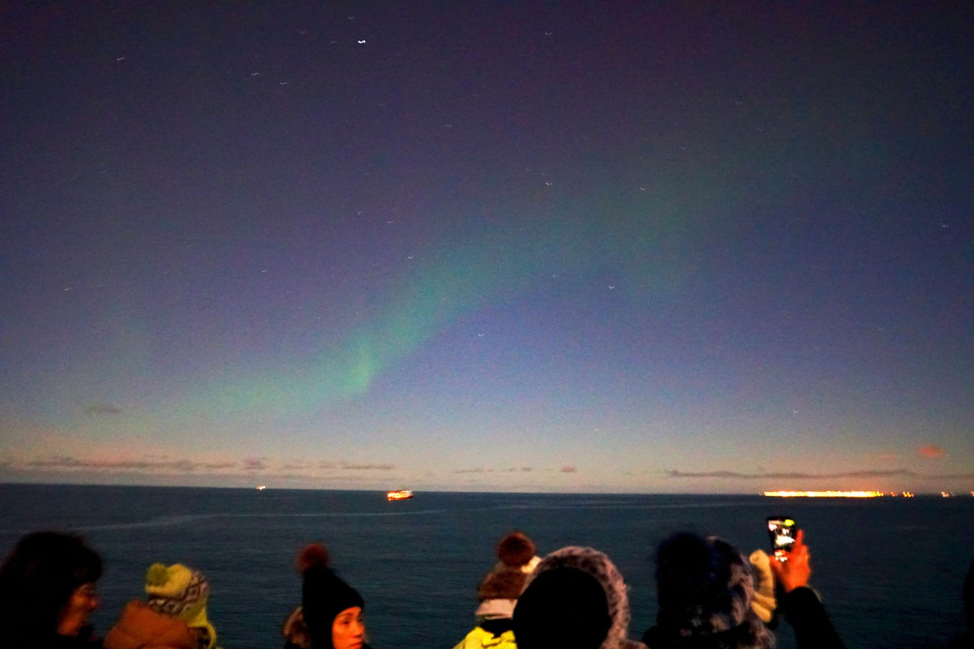 People watching the aurora borealis over the ocean
