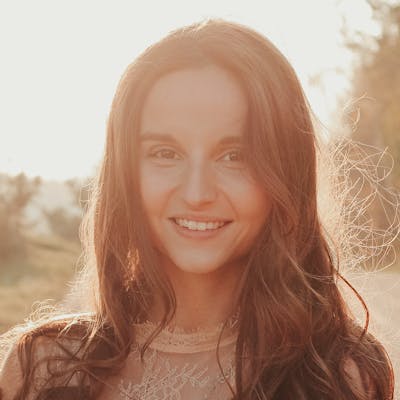 A smiling woman with long brown hair in the sunlight